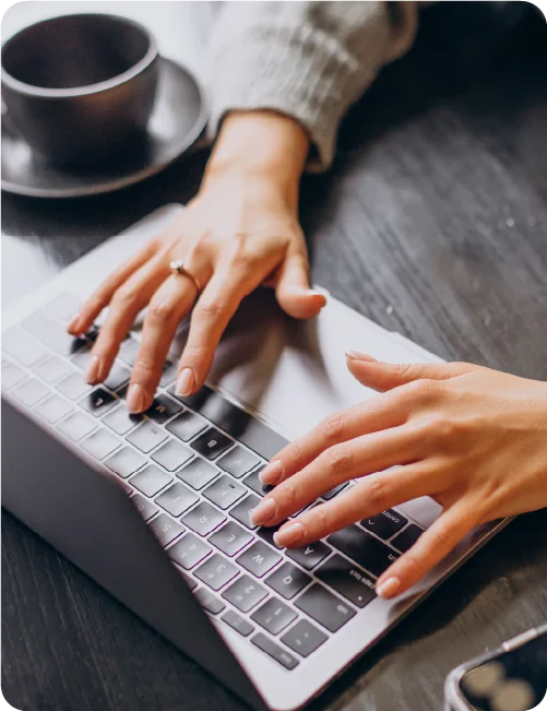 Laptop being used at a wooden desk by a primary care worker